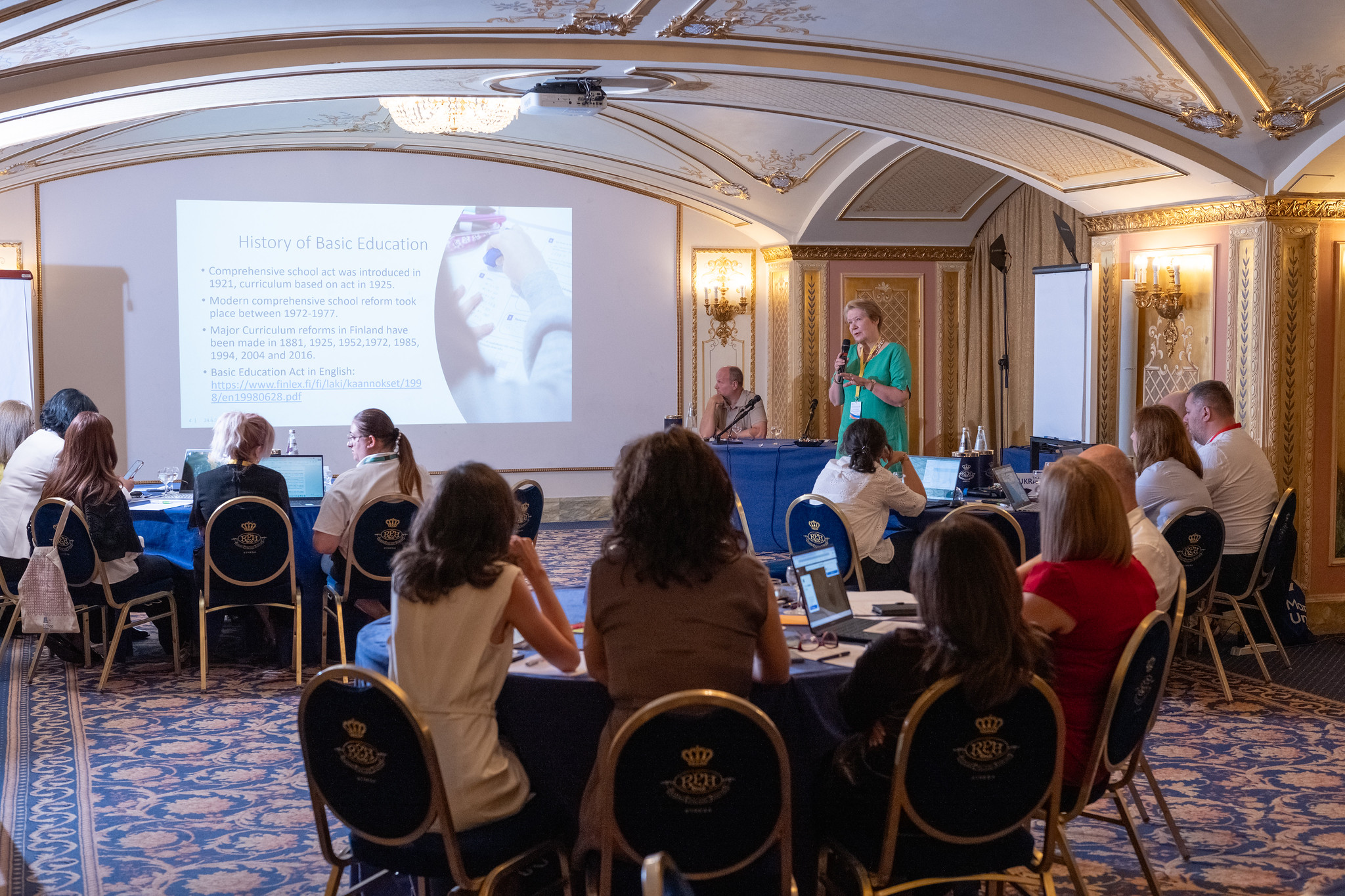 Seated attendees listen in the Hotel Regina in Stresa, Italy, as Director for International Relations at the Ministry of Education and Culture of Finland, Jaana Palojärvi, addresses them with a slide presentation as part of an ETF Policy Lab on education  