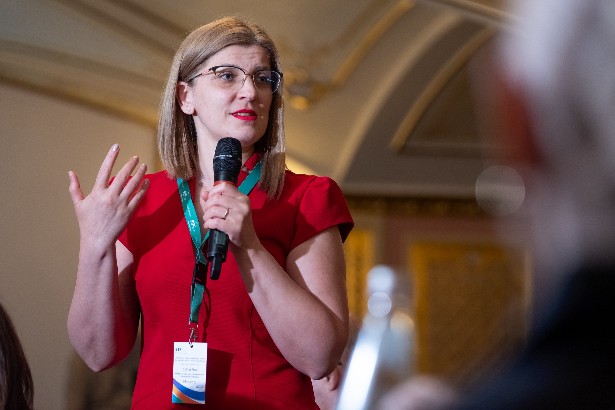 Romanian Minister, Galina Rusu, dressed in red addresses attendees at the June education Policy Lab in Stresa, Italy