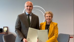 RCC Secretary General Amer Kapetanović (in grey) and ETF Director Pilvi Torsti (in yellow) stand side by side holding matching RCC publications