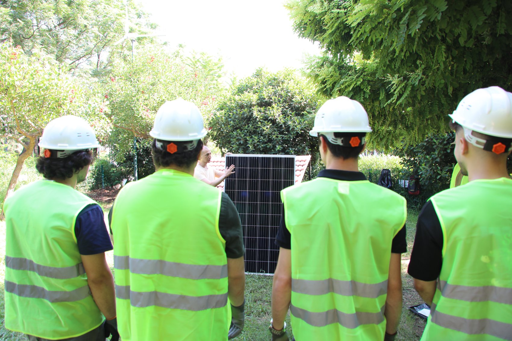 A teacher providing technical training on solar panels to a group of students