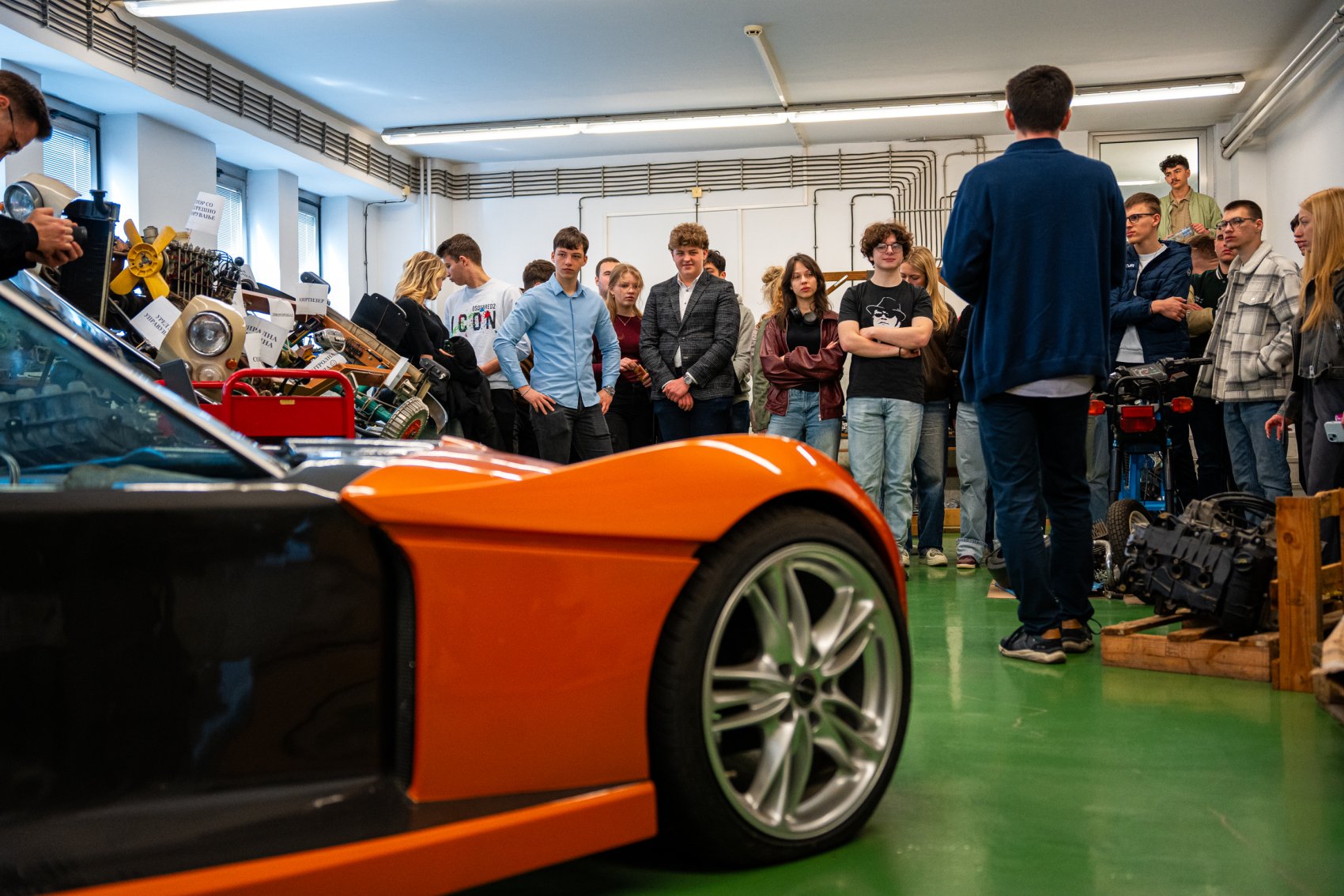 A teacher shows students an eco-friendly sports car made from recycled metal