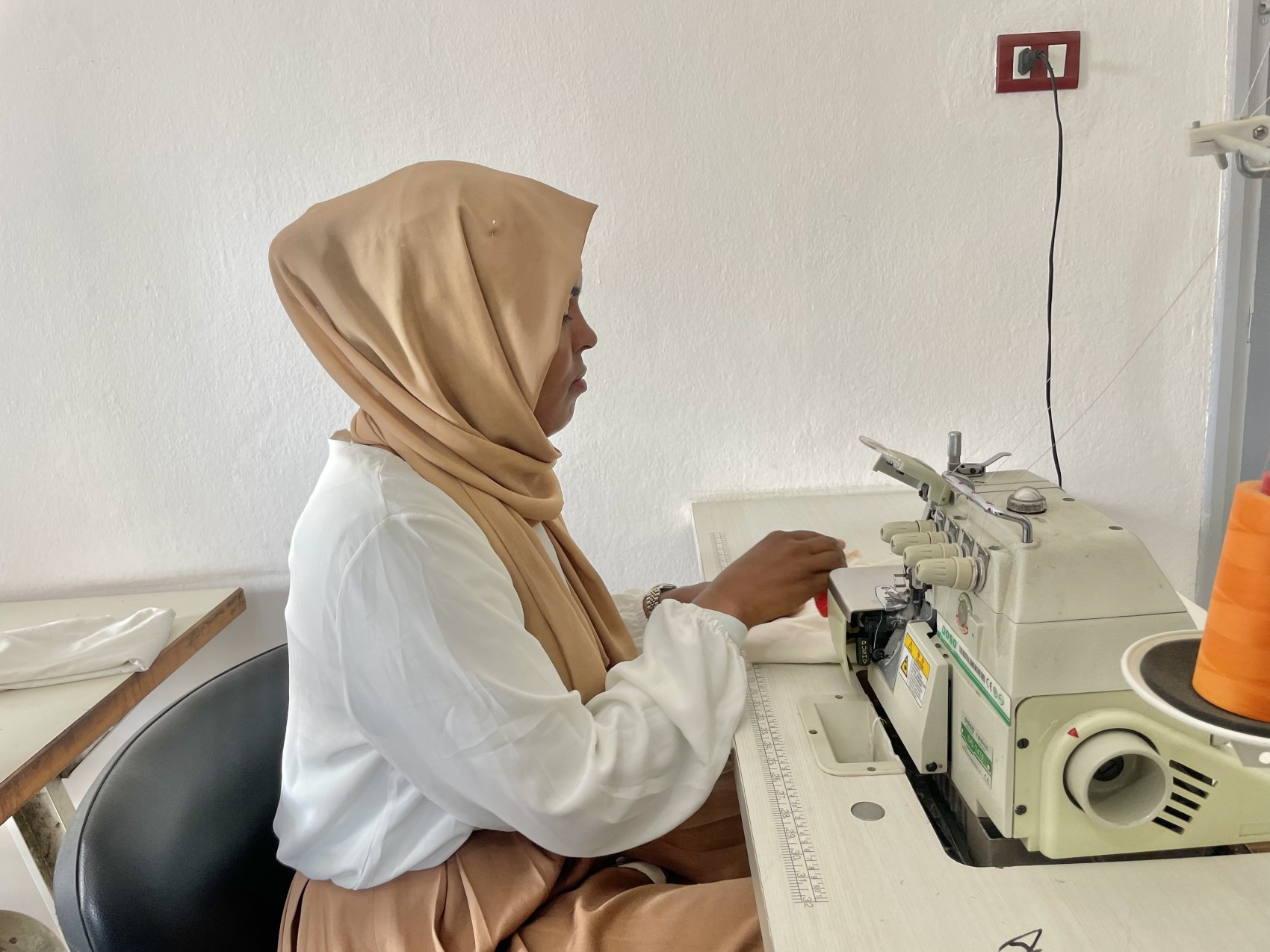 A Tunisian lady at a sewing machine learning new skills