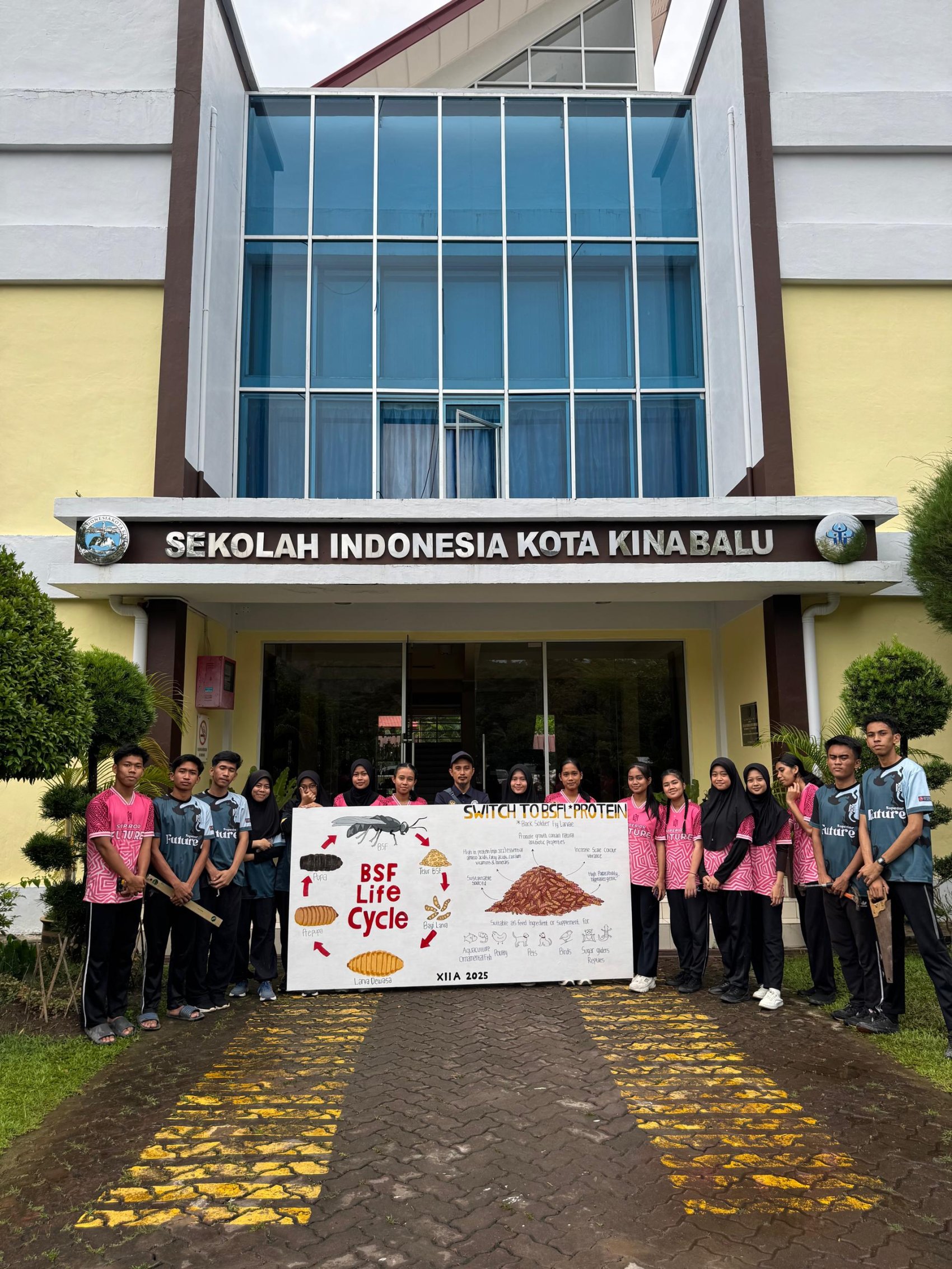 Students of SIKK school in Malaysia with a lifecycle diagram of the black soldier fly as part of their sustainable compost project
