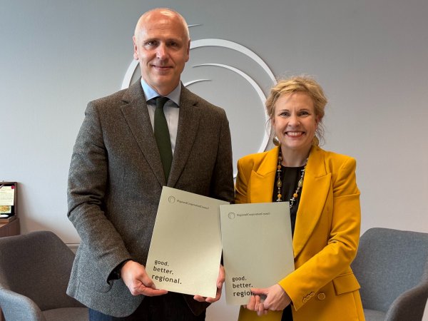 RCC Secretary General Amer Kapetanović (in grey) and ETF Director Pilvi Torsti (in yellow) stand side by side holding matching RCC publications