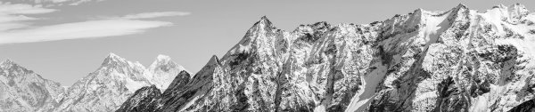 Black and white photo of a mountain range with snow, against a clear sky.
