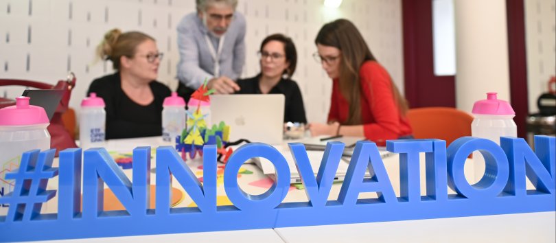 Members of ETF's excellence network discussing ideas with an innovation sign on the desk